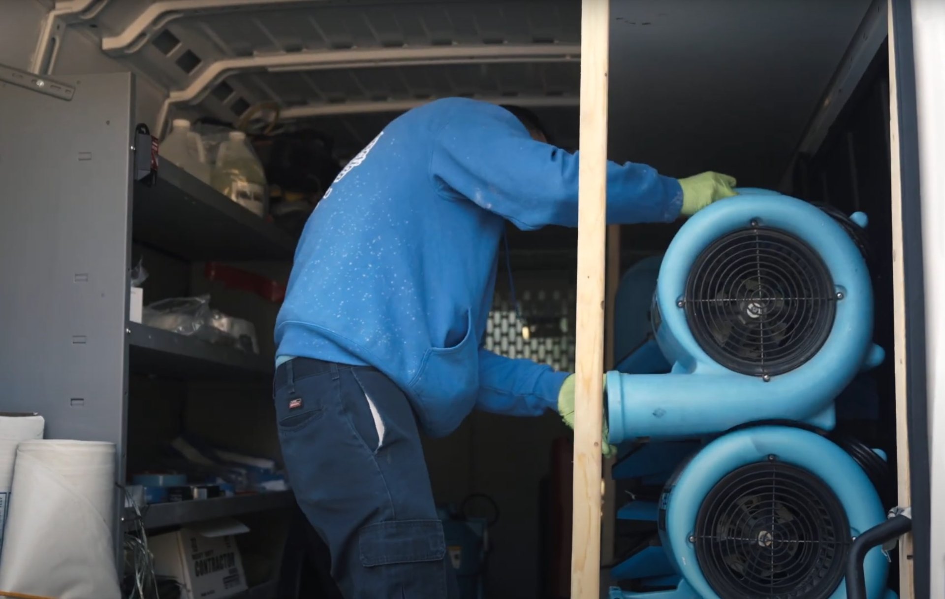 Professional water damage restoration team using specialized drying equipment Water damage restoration technician working with industrial drying fans and equipment